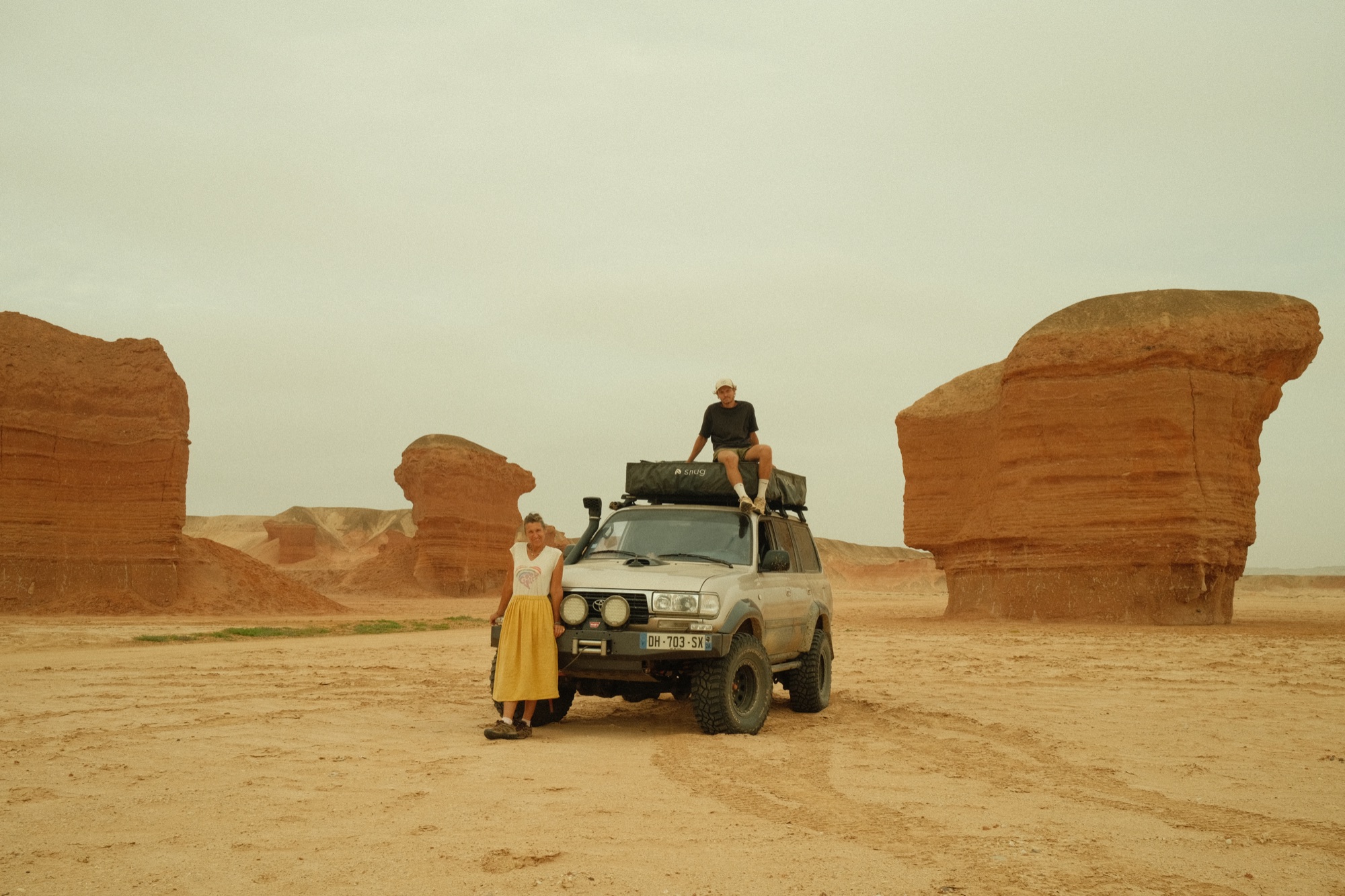 Tom and Charlotte in front of their Toyota Land Cruiser, in a red sandstone canyon